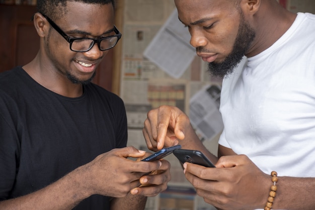 携帯電話でコンテンツを共有する2人の若いアフリカ人男性の浅い焦点