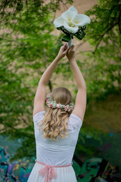 公園で花束を投げる若いブロンドの花嫁の浅い焦点