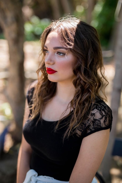 Foto gratuita fuoco poco profondo di una giovane donna caucasica che indossa un abito nero con rossetto rosso in primo piano