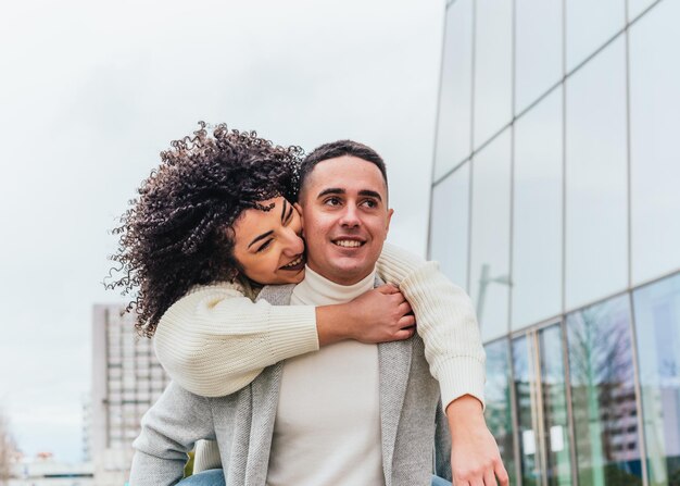 Shallow focus of a young smiling man carrying his girlfriend on his back