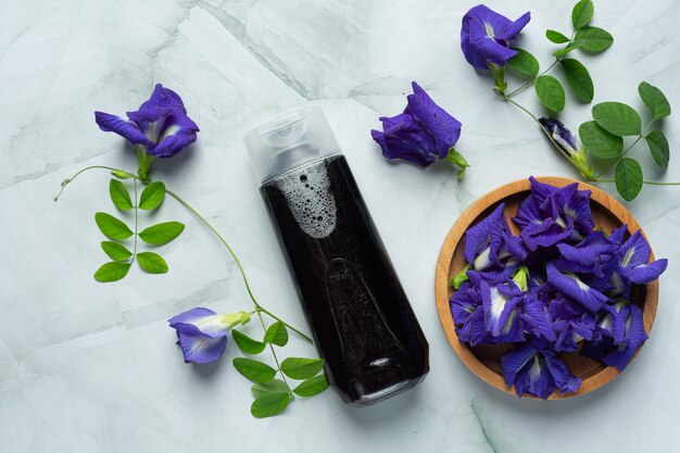 Бутылка шампуня Butterfly Pea Flower на белом мраморном фоне