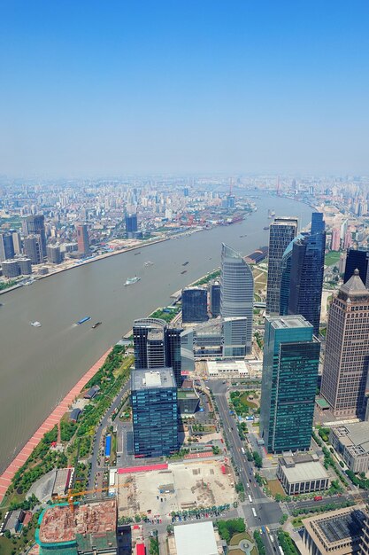 Shanghai city aerial view with urban architecture over river and blue sky in the day.