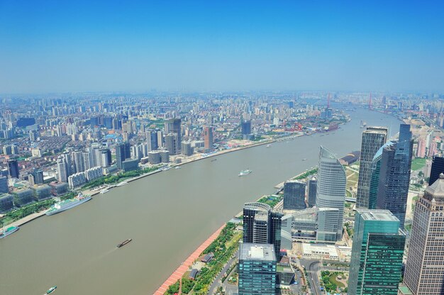 Shanghai city aerial view with urban architecture over river and blue sky in the day.