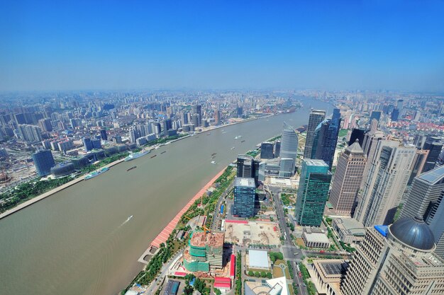 Shanghai city aerial view with urban architecture over river and blue sky in the day.