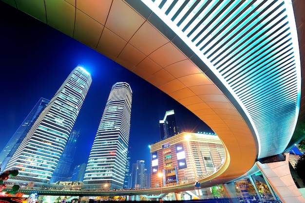 Шанхай ночью с городским небоскребом и современным городским пейзажем на улице.