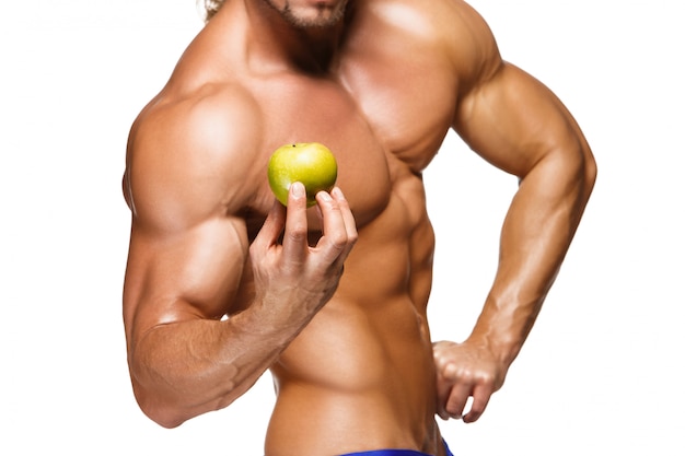 Shaped and healthy body man holding a fresh apple fruit,  isolated on white wall