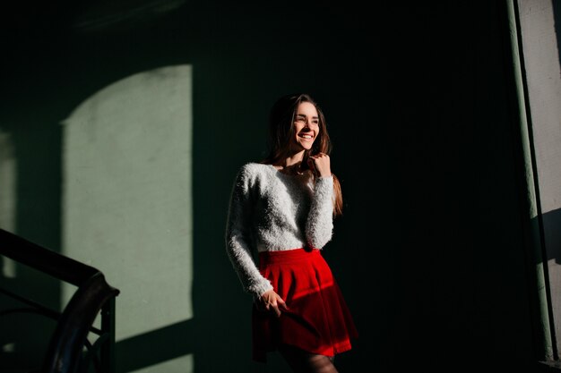 暗闇の中で立って笑顔の赤いスカートの格好の良い女の子