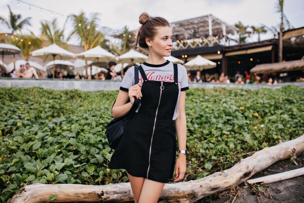 Shapely girl wears trendy clothes standing near lawn and looking away. Outdoor portrait of good-looking caucasian lady chilling in city.