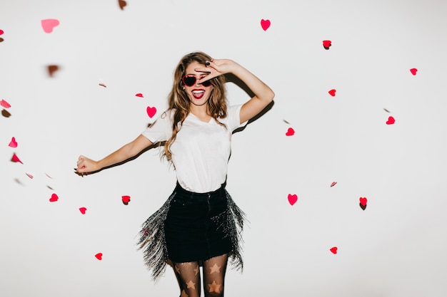 Free photo shapely happy woman jumping in studio decorated with hearts