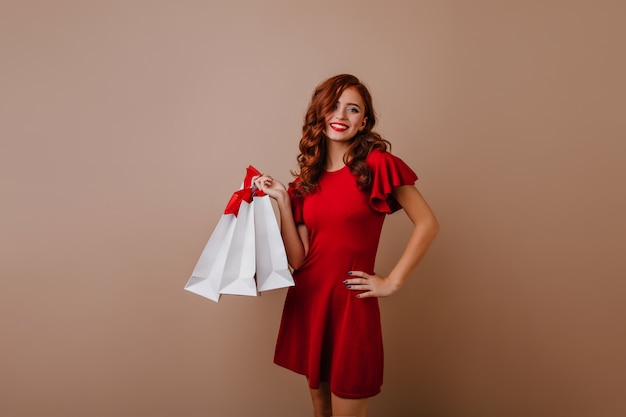 Shapely red-haired girl posing after shopping.  female shopaholic wears red dress.