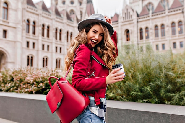 Shapely woman with wavy hair laughing while exploring old part of city