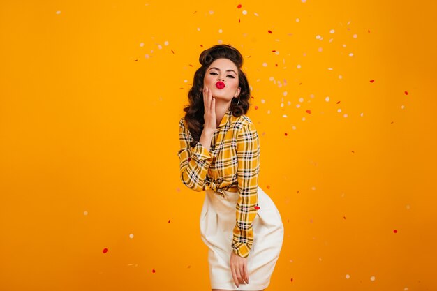 Shapely young lady posing with kissing face expression. Studio shot of adorable pinup girl in white skirt.