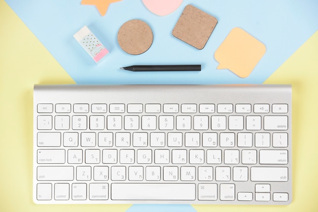 Shapes; eraser and pencil near the white keyboard on dual backdrop