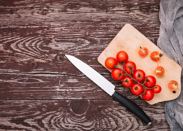Острый нож и помидоры черри на разделочную доску на деревянной поверхности