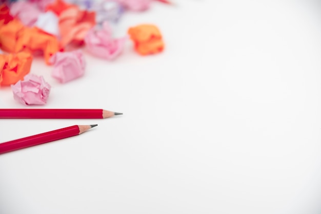 Sharp red pencils and crumple paper on white backdrop