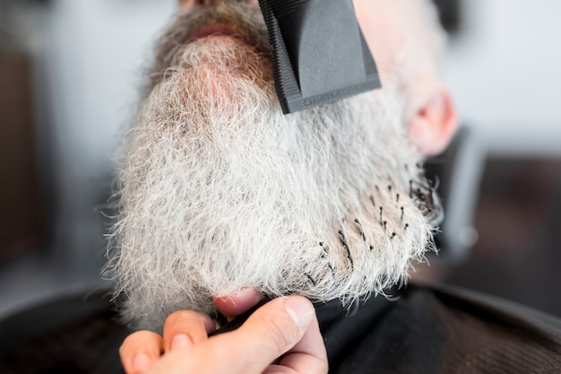 Shaving beard of senior client in barbershop