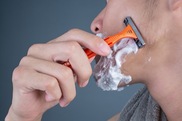 Shaving handsome guy shaved on the face on gray