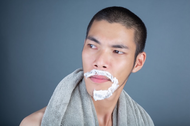Красивый бритый парень побрился на лицо на сером