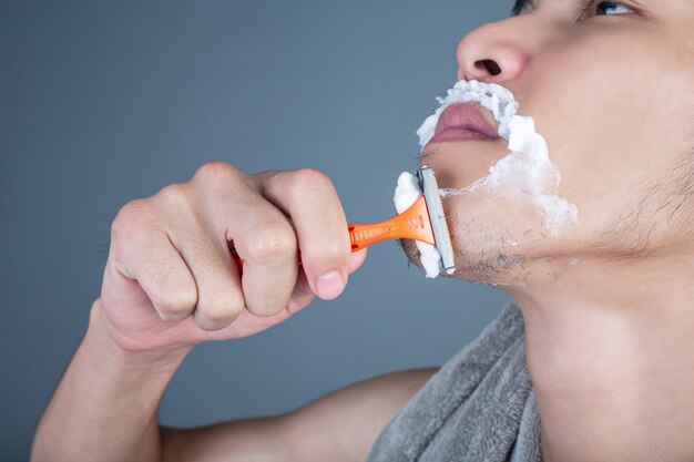 Shaving handsome guy shaved on the face on gray