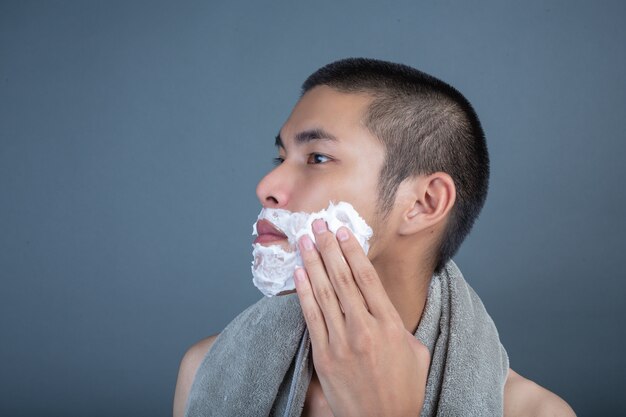 Shaving handsome guy shaved on the face on gray