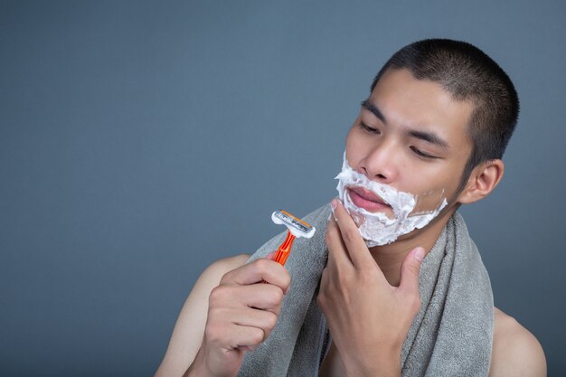 Shaving handsome guy shaved on the face on gray