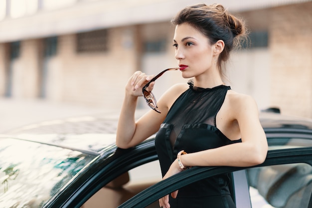 She is ready to win the world - confident woman standing in the dor of car