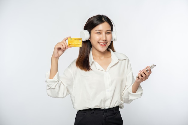 She was dressed in a white shirt and dark pants to go shopping and hold a credit card and smartphone