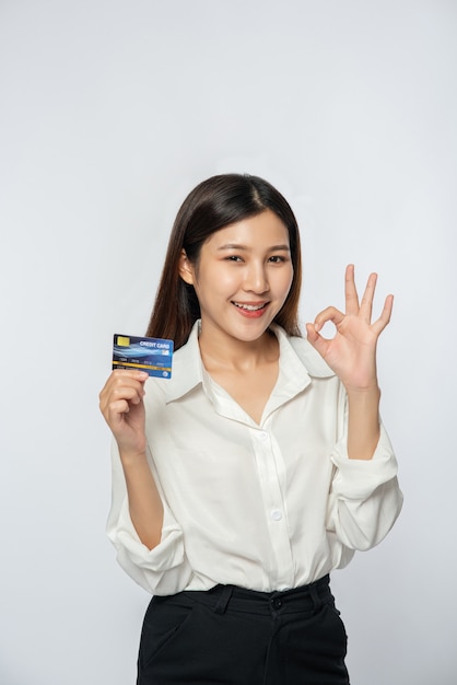 She was dressed in a white shirt and dark pants to go shopping and hold a credit card