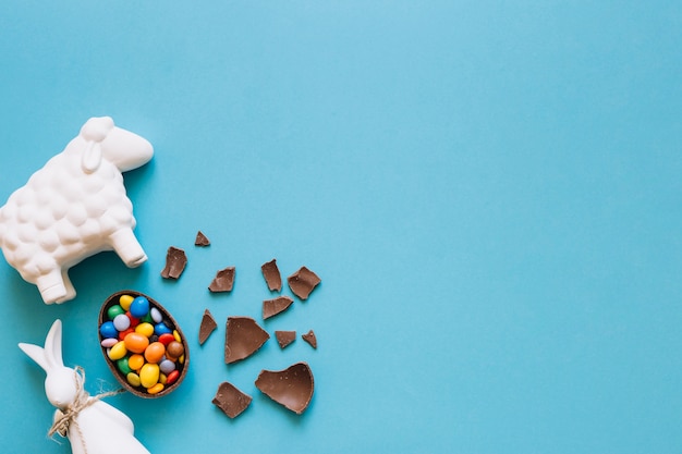 Sheep and bunny statuettes near chocolate egg