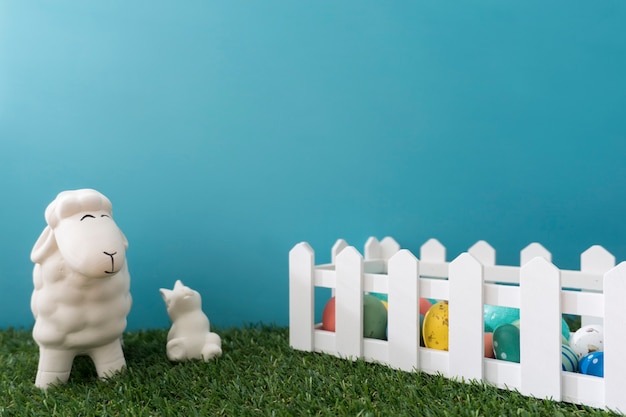 Free photo sheep and rabbit close to a wooden fence with easter eggs