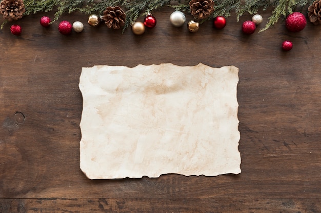 Sheet of paper with shiny baubles and cones 