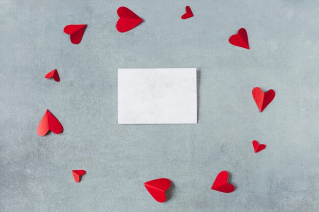 Лист между красными бумажными символами сердца в форме круга