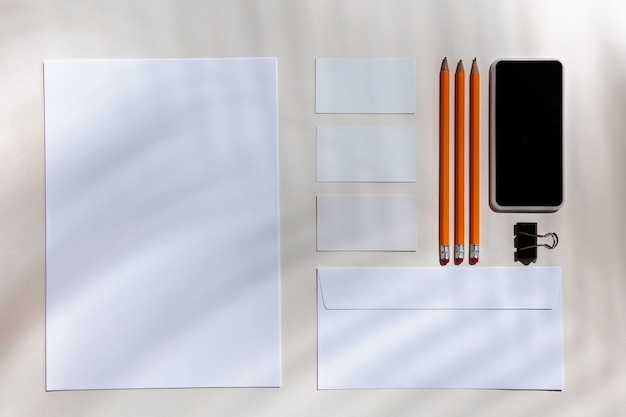 Sheets, gadgets and work tools on a white table indoors.