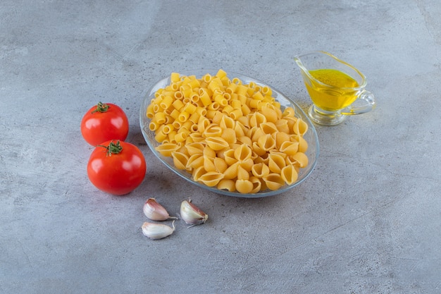 Free photo shell uncooked pasta with raw dry ditali rigati in a glass bowl .