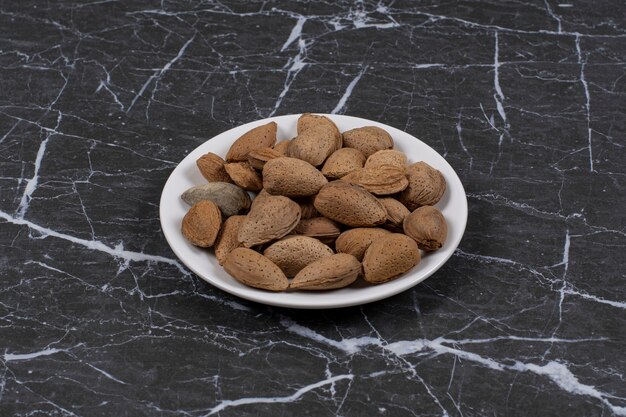 Shelled almonds in the plate, on the marble surface