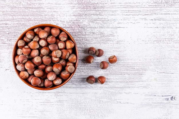 Shelled hazelnuts in a bowl on a white wooden table. top view.