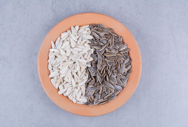 Shelled sunflower seeds on a plate on the marble surface