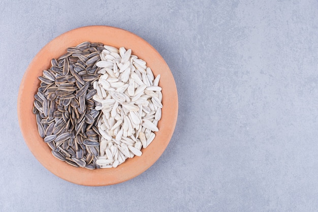 Shelled sunflower seeds on plate on marble.