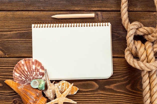 Shells and notepad on wooden table top view with copy space