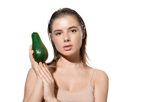 Shining. Beautiful young woman with fresh avocado over white