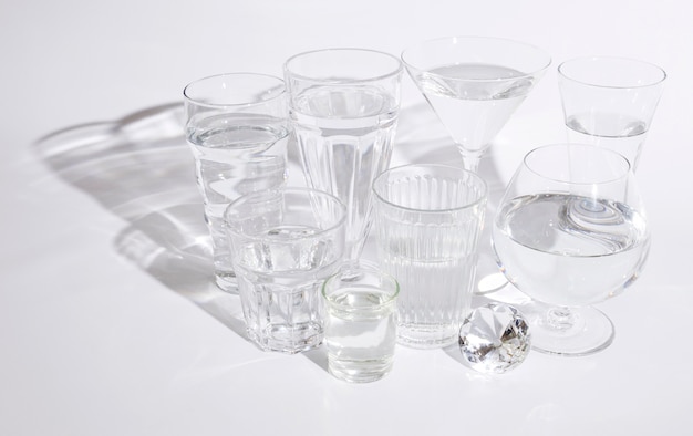 Shining diamond with glasses of water on white background