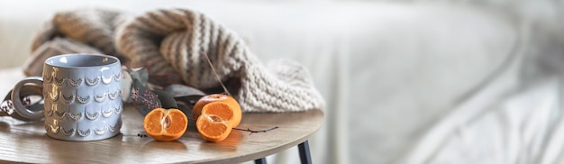 A shiny cup a knitted element and tangerines on the table in the interior