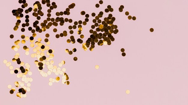 Shiny golden confetti on pink background