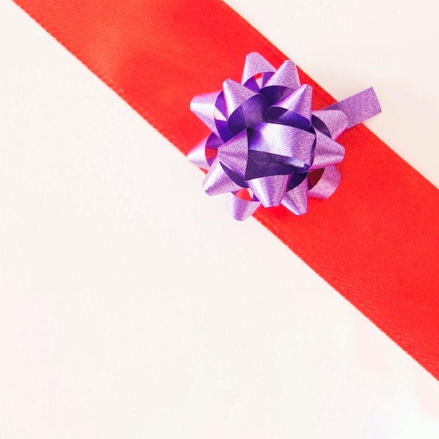 Shiny purple ribbon on red striped over white background