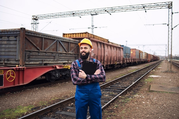 Shipping worker looking at train coming to the station and organizing goods distribution and export