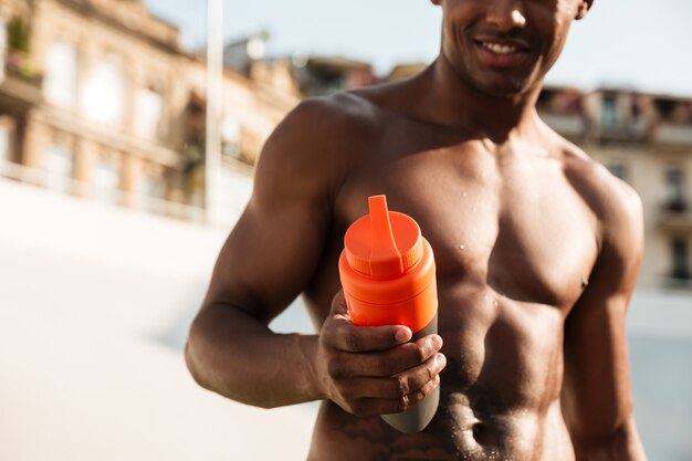 Shirtless african sports man holdin bottle of water