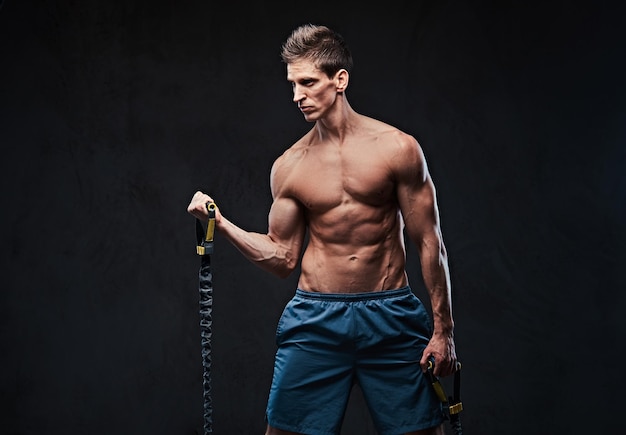 Shirtless athletic male warms up with the latex resistance band.
