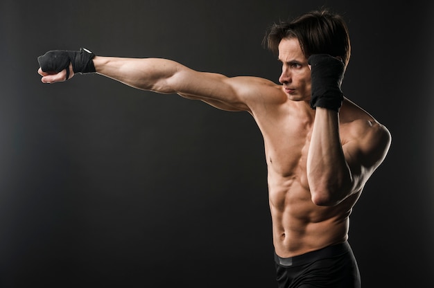 Shirtless athletic man boxing with copy space