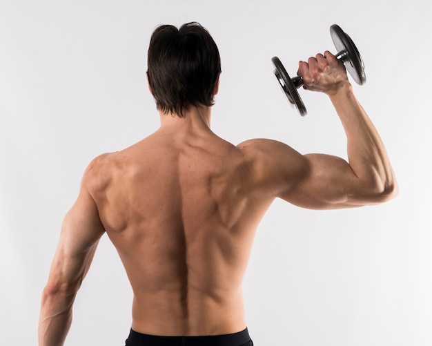 Shirtless athletic man showing off back muscles while holding weight
