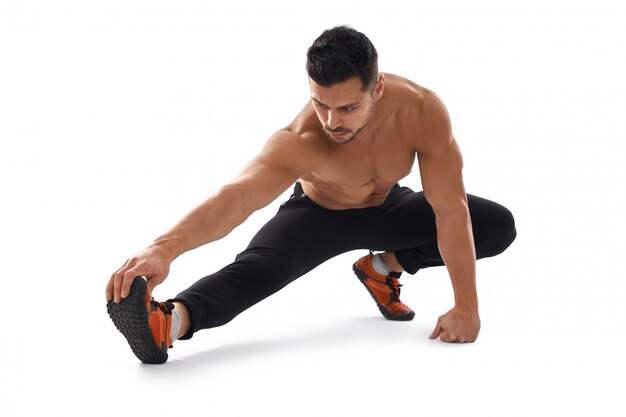 Shirtless bodybuilder stretching on floor.